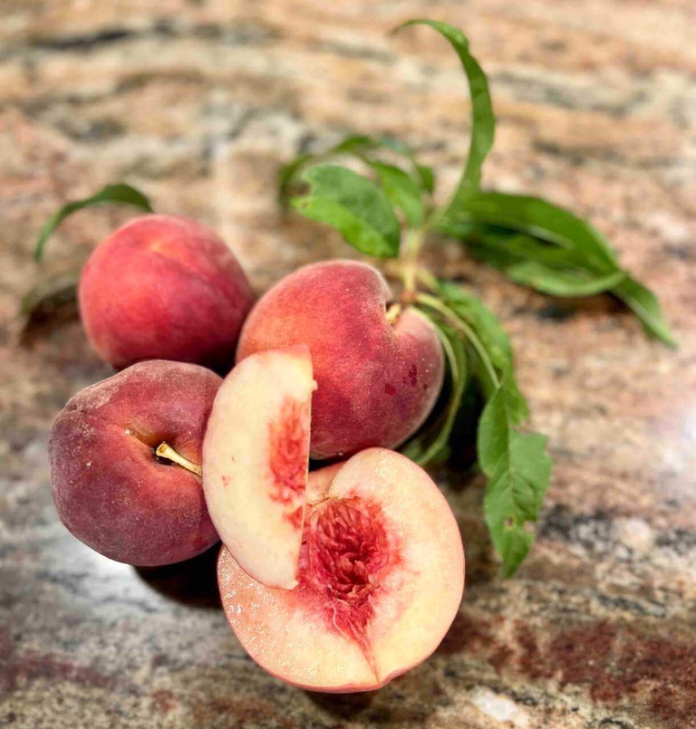 Freestone Bennett Peaches sliced in half to show the beautiful and honey like flesh. 